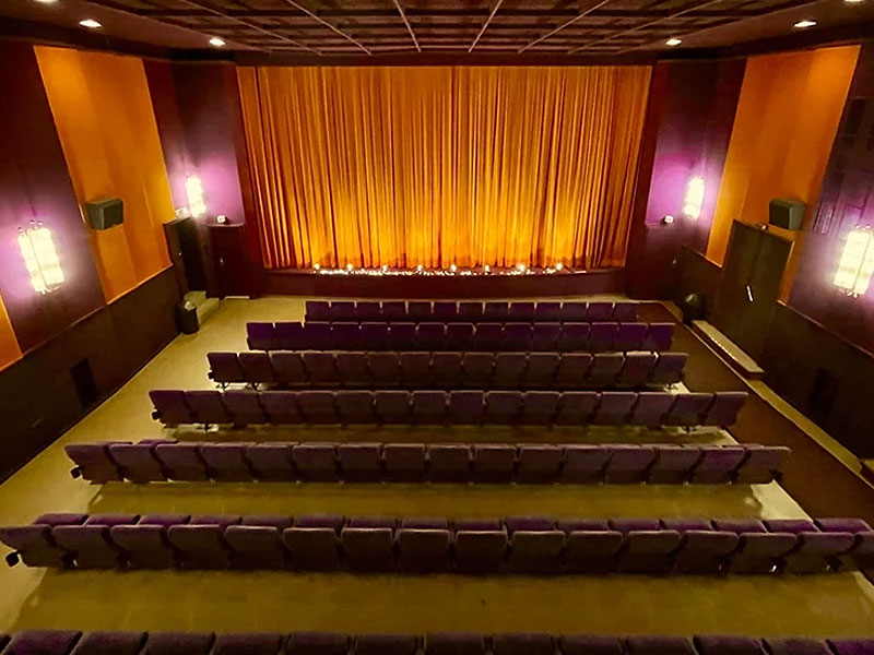 Innenansicht des Kulturtheaters Tutzing mit Sitzreihen und geschlossenem Bühnenvorhang